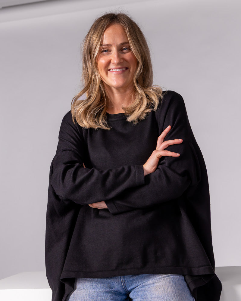 Black oversized crew neck knit jumper featuring fitted sleeves and a draped high-low hemline.