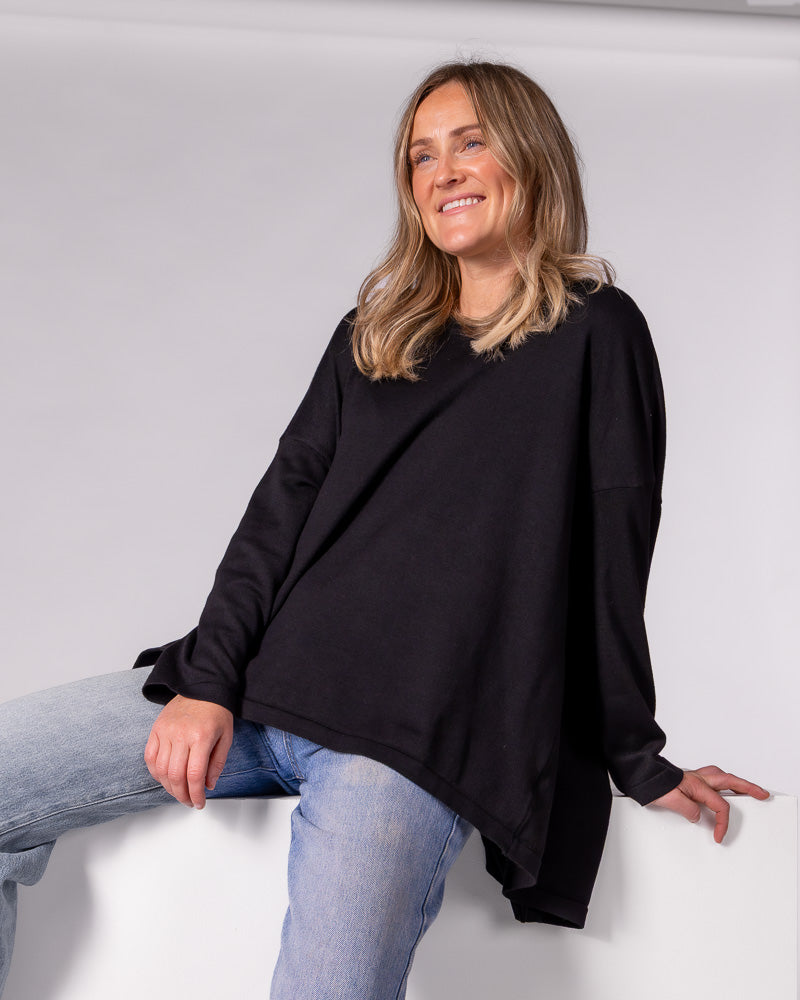Oversized black cotton-blend knit jumper with a crew neckline, long sleeves, and a gently draped high-low hem.