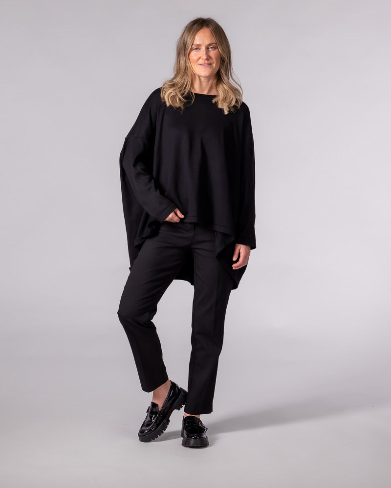 Black oversized knit jumper featuring a classic crew neckline, long sleeves, and a draped high-low hemline.