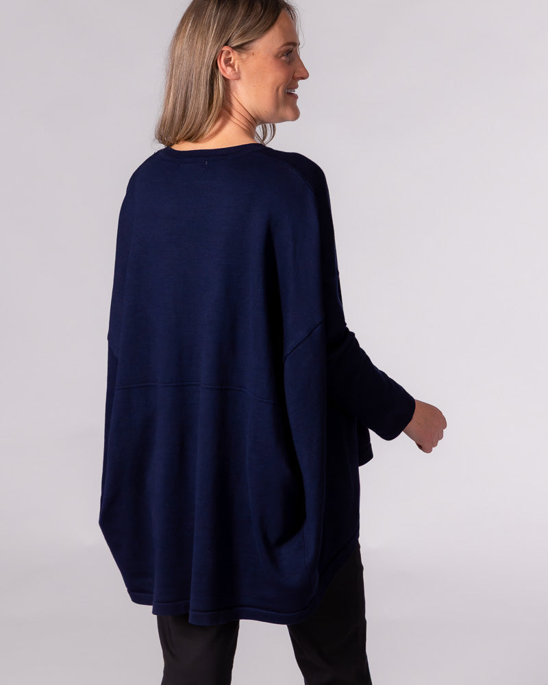 Back view of the oversized navy cotton-blend jumper showing dropped shoulders, a horizontal back seam, and a draped hem.