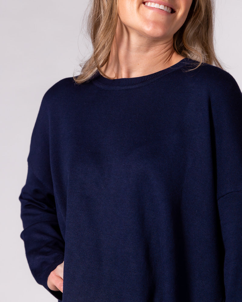 Oversized navy blue knit jumper featuring a ribbed crew neckline, dropped shoulder seams, and a relaxed fluid drape.