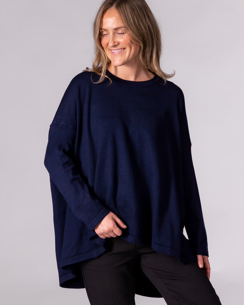 Navy oversized crew neck knit jumper featuring dropped shoulders, long sleeves, and a draped high-low hem.