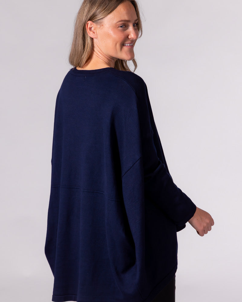 Oversized navy cotton-blend knit jumper viewed from the back, featuring dropped shoulders and a horizontal lower seam.