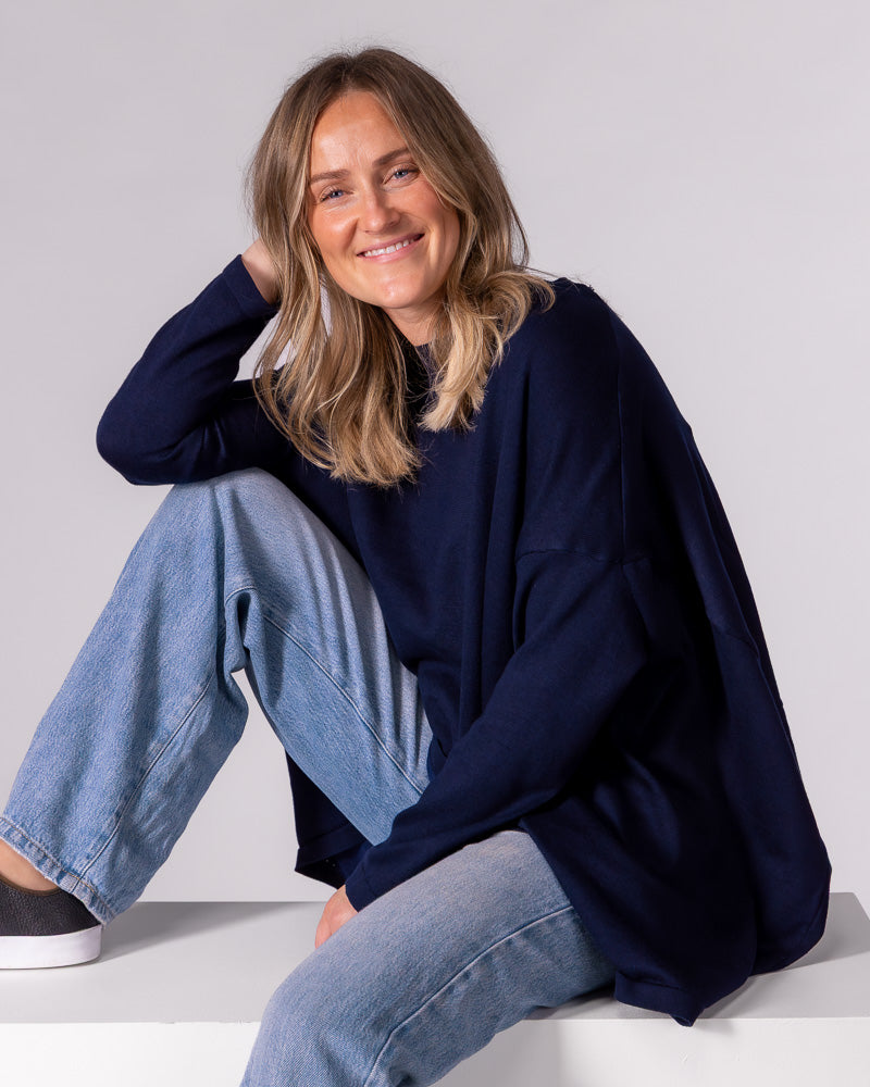 Navy oversized knit jumper featuring a classic crew neckline, long fitted sleeves, and a draped high-low hem.