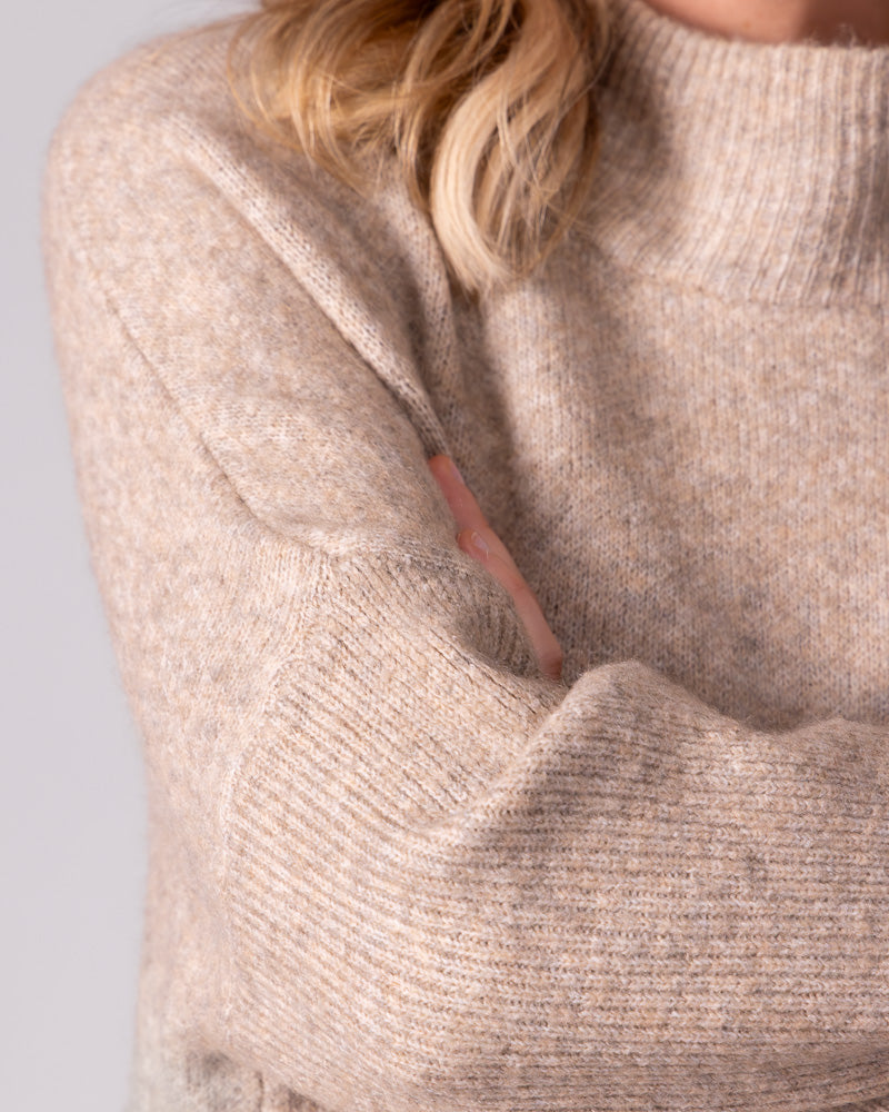 Beige brushed knit jumper featuring a ribbed funnel neck, prominent drop shoulder, and contrasting ribbed sleeve.