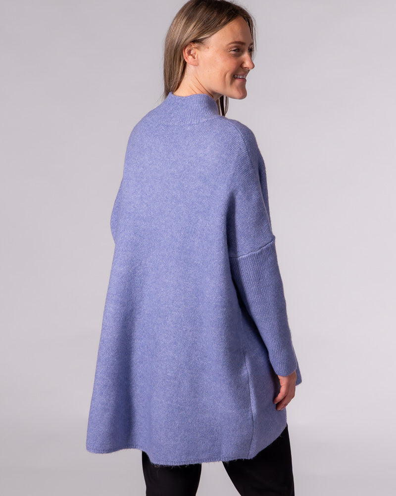 Back view of a blue oversized brushed knit jumper featuring a ribbed funnel neck, dropped shoulders and ribbed sleeves.