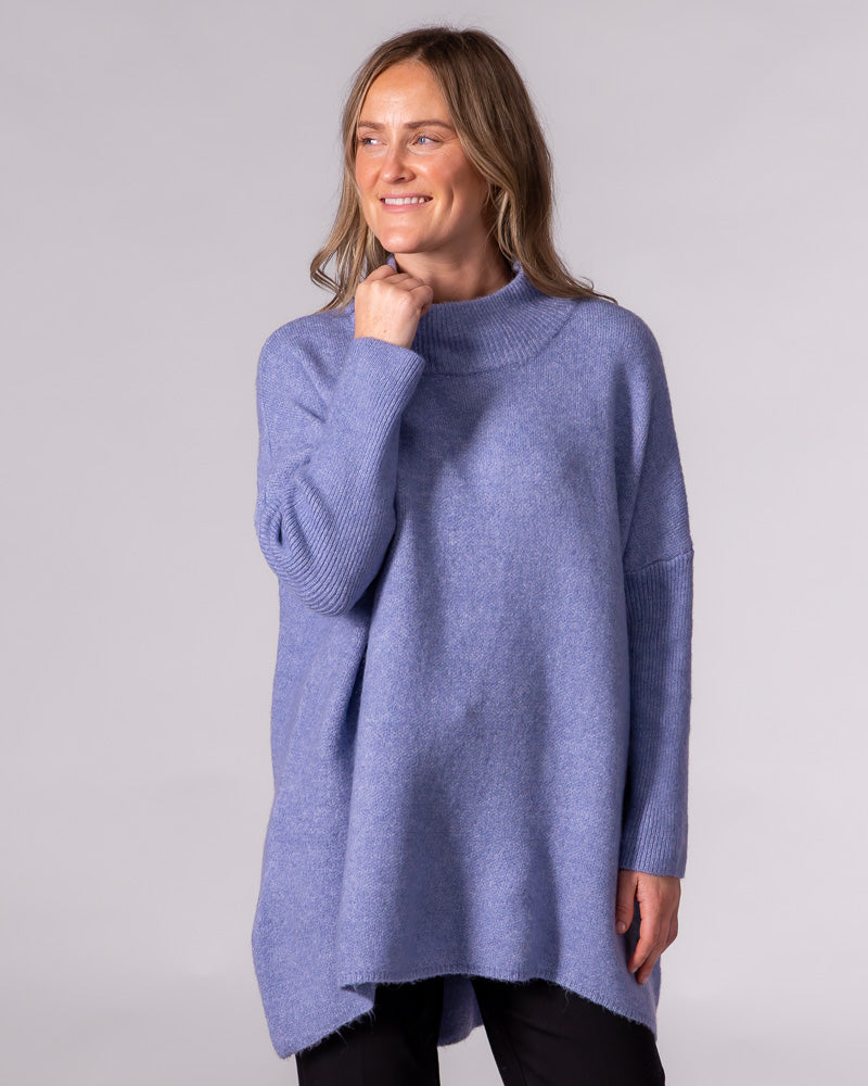 Oversized blue brushed knit jumper featuring a ribbed funnel neck, drop shoulders, and full-length ribbed sleeves.