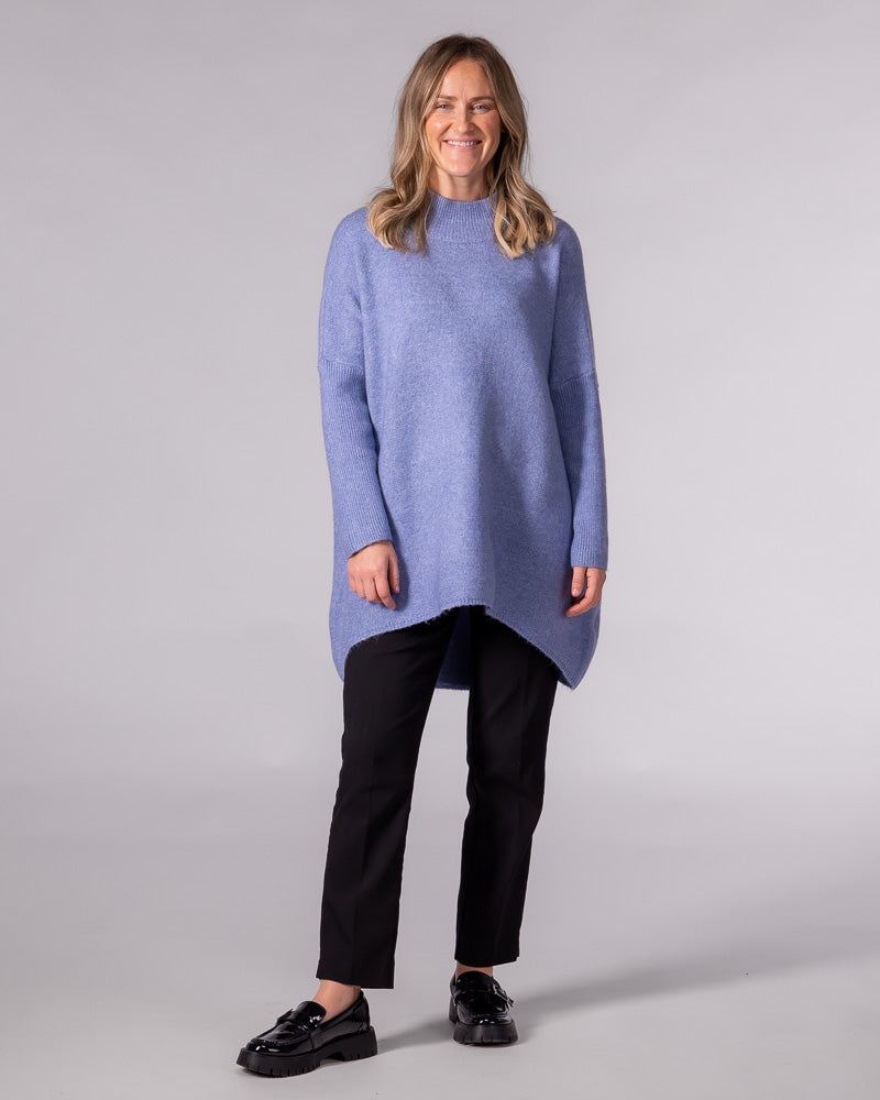 Oversized blue brushed knit jumper featuring a ribbed funnel neck, relaxed drop shoulders, and a draped high-low hem.