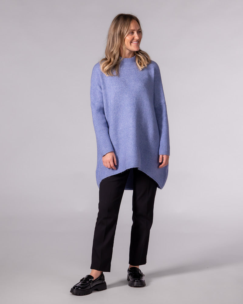 Oversized blue knit jumper showcasing a ribbed funnel neck, drop shoulders, ribbed sleeves and a brushed high-low hem.