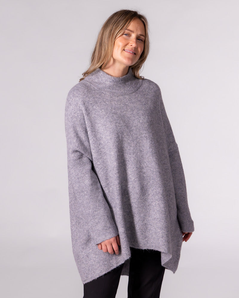 Oversized grey brushed knit jumper featuring a ribbed funnel neck, drop shoulders, ribbed sleeves, and a high-low hem.