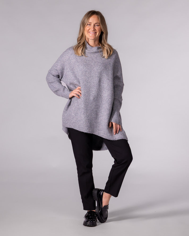 Grey oversized brushed knit jumper featuring a ribbed funnel neck, drop shoulders, and a high-low hemline.