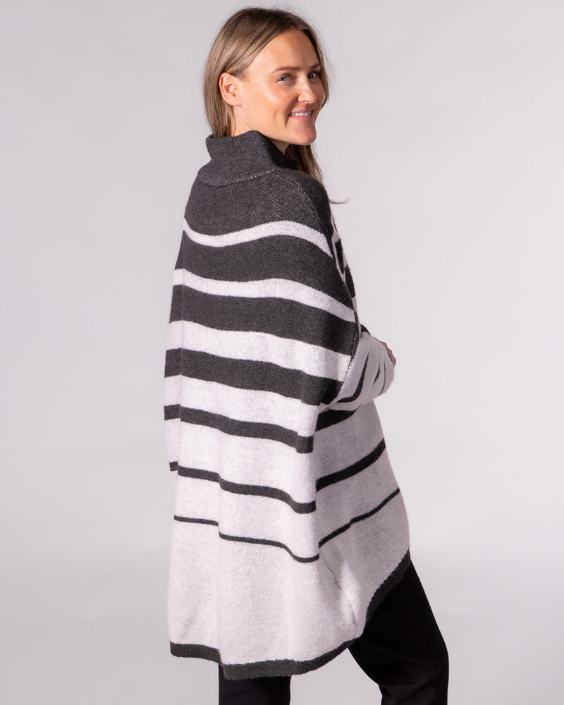 Oversized charcoal and white striped brushed knit jumper showcasing a funnel neck and extended high-low back hemline.