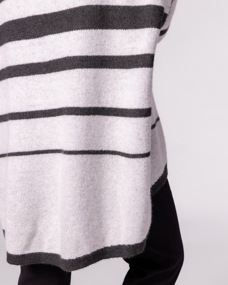 Side detail of an oversized brushed knit jumper in charcoal stripe showing the relaxed drape and high-low hemline.