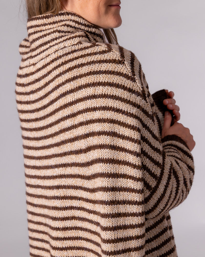 Oversized chocolate and beige striped knit jumper highlighting the soft funnel neck and drop-shoulder sleeve.