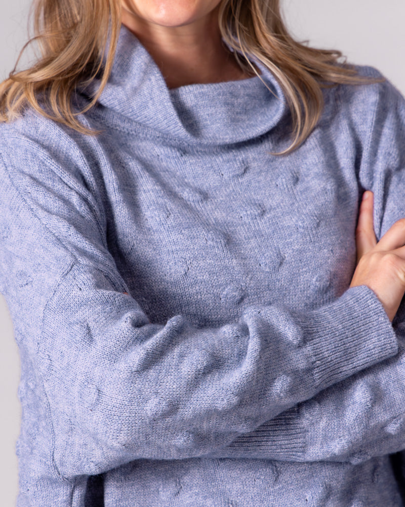 Light blue jumper with a textured bubble knit finish, featuring a relaxed funnel neck, drop shoulders and ribbed cuffs.