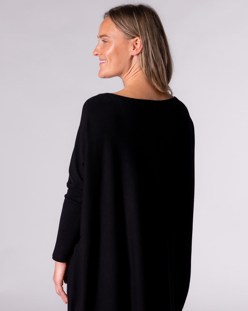 Rear angle showing how the soft cotton fabric falls gracefully from the shoulders of this relaxed black knit top.