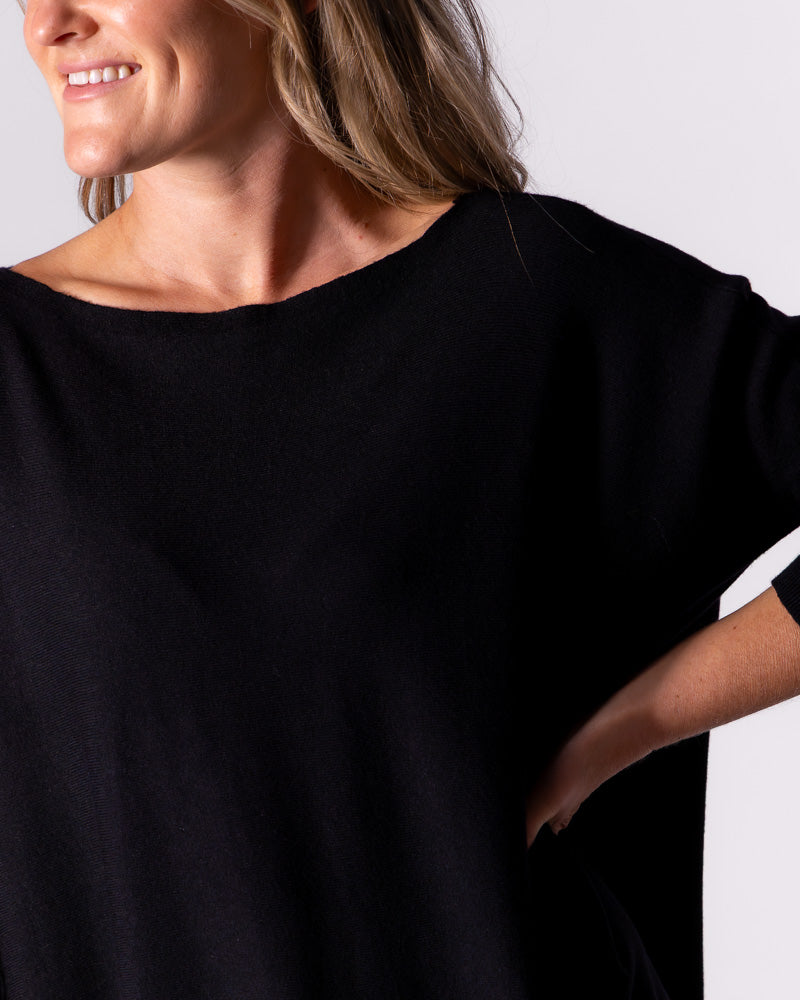 Front detail shot capturing the elegant boat neckline and comfortable drop shoulders on the black cotton knit top.