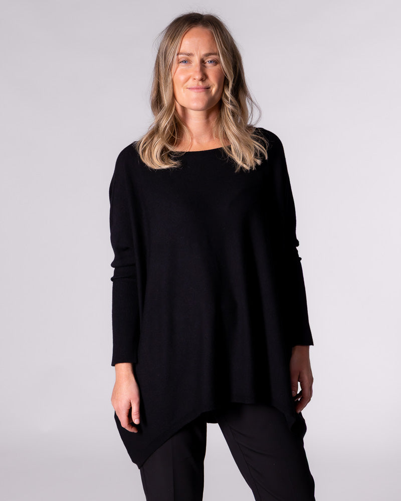 Front facing view of the black knit top displaying the hi-low hem design, sitting noticeably higher at the front.