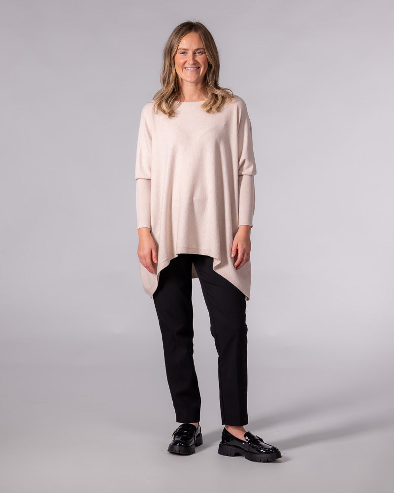 Oversized blush cotton jumper featuring a wide boat neckline, drop shoulders, fitted sleeves, and a draped hi-low hem.
