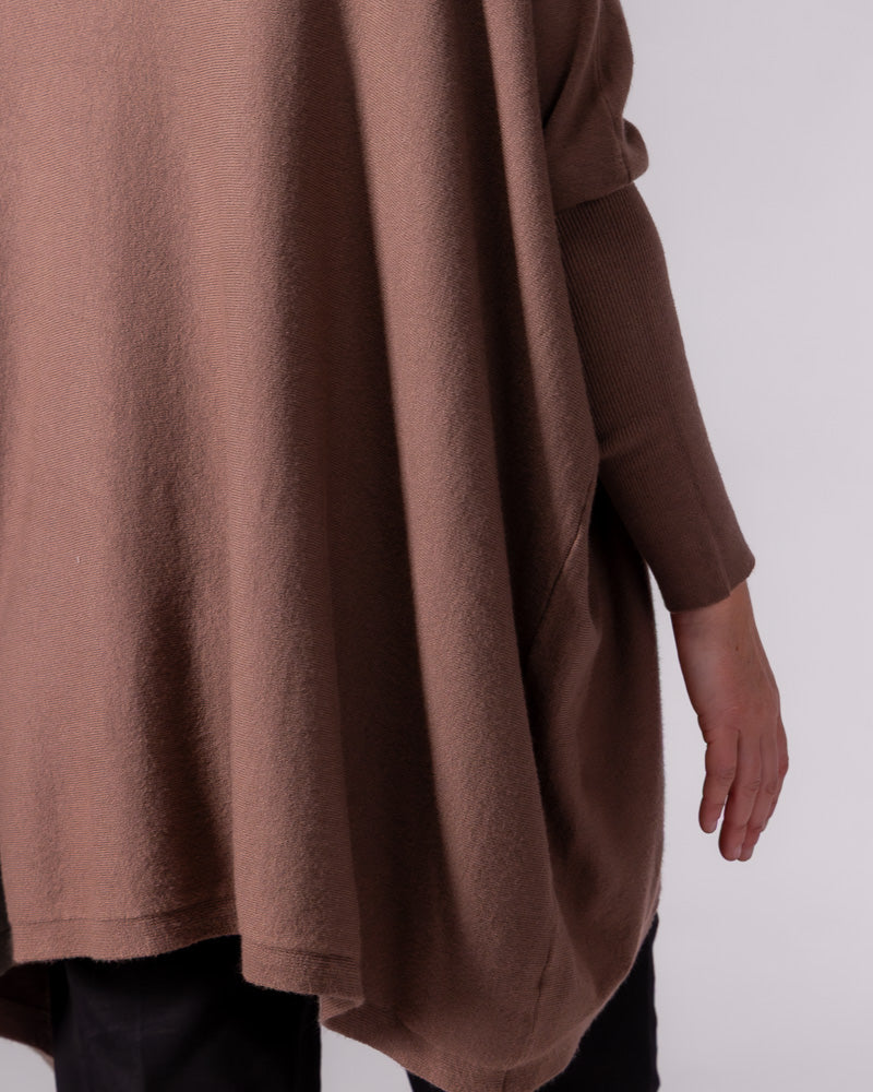 Close-up of the oversized brown cotton knit jumper highlighting the soft draped body, hi-low hem, and fitted sleeve.