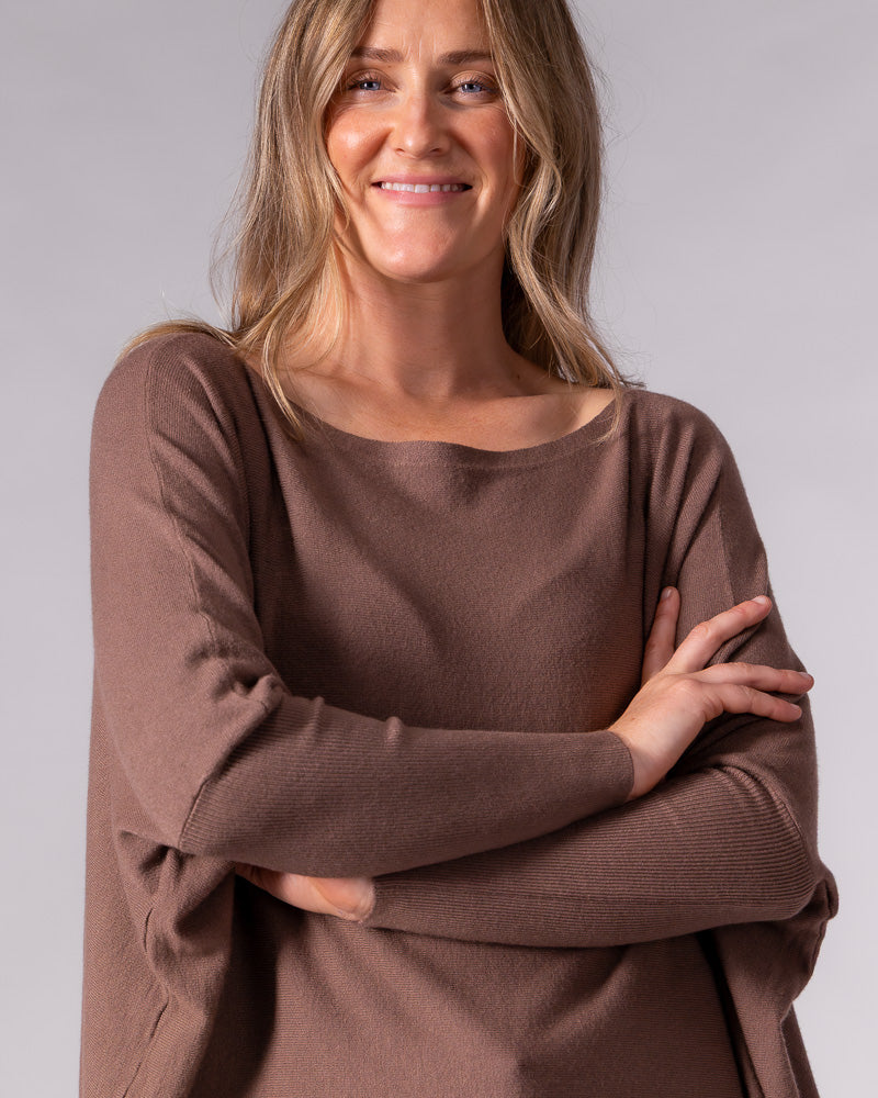 Oversized brown cotton knit jumper featuring a wide boat neckline, drop shoulders, and fitted ribbed sleeves.