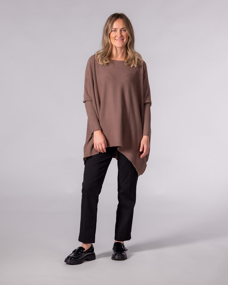 Oversized brown cotton jumper with a wide boat neckline, drop shoulders, fitted sleeves, and a draped hi-low hem.