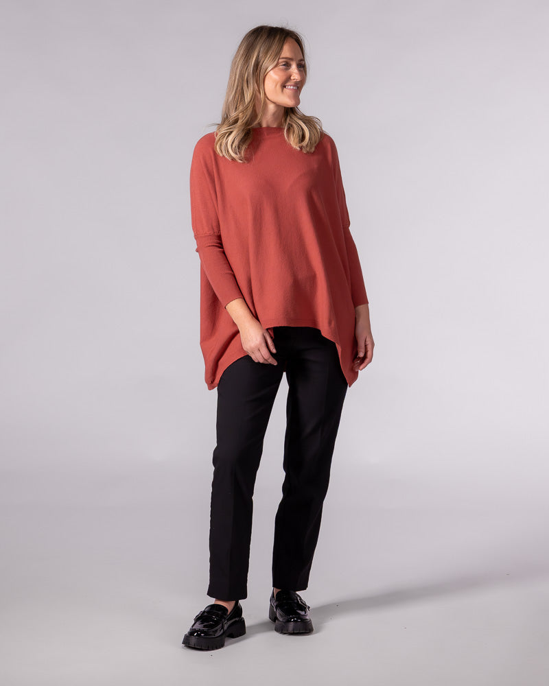 Oversized burnt orange cotton knit jumper featuring a wide boat neckline, drop shoulders, and fitted sleeves.