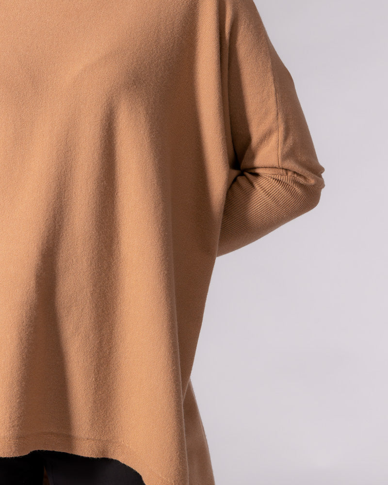 Oversized camel cotton knit jumper displaying a relaxed body drape and a closely fitted ribbed sleeve.