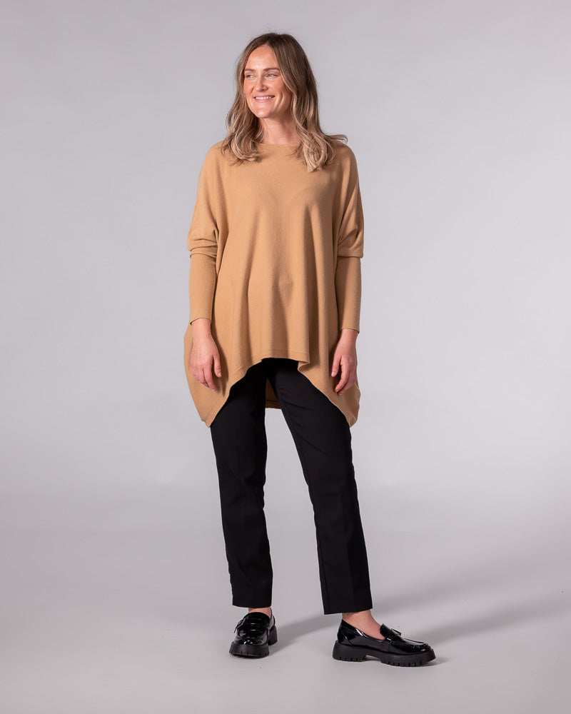 Oversized camel cotton knit jumper with a wide boat neckline, drop shoulders, fitted sleeves, and a draped hi-low hem.