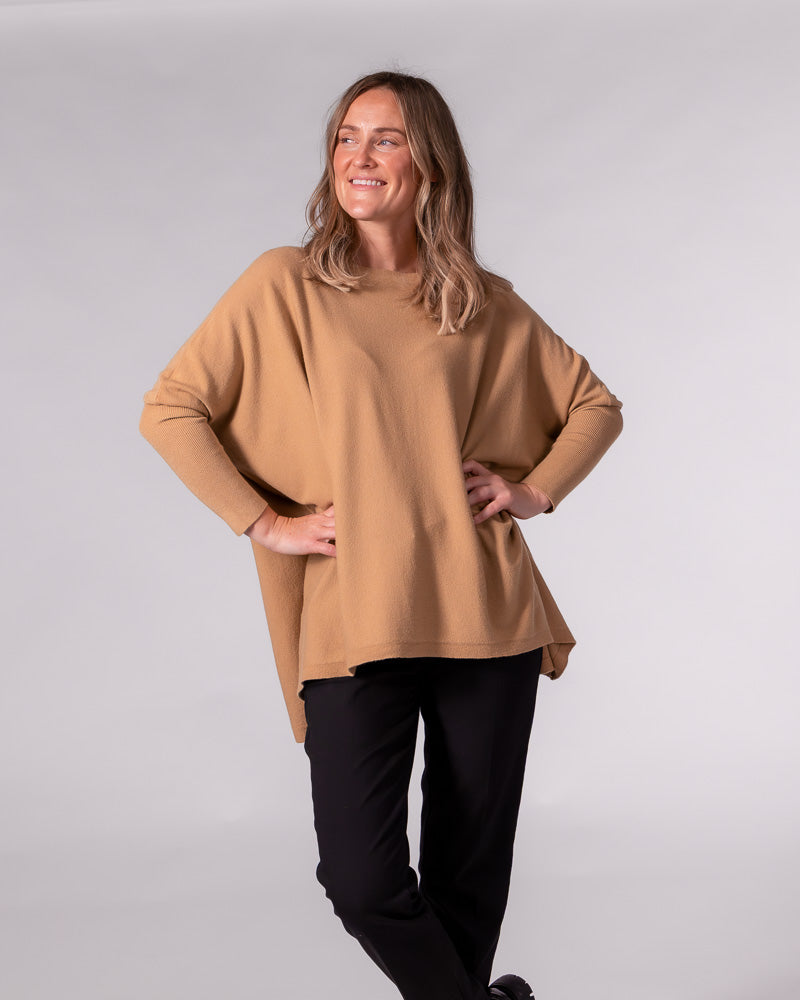 Oversized camel cotton knit jumper featuring a wide boat neckline, relaxed drop shoulders, and long fitted sleeves.