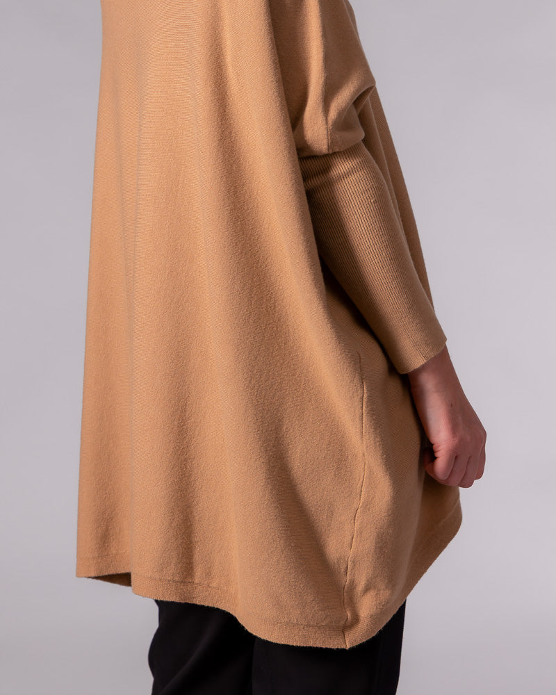 Camel cotton knit jumper featuring an oversized draped back silhouette, curved hi-low hem, and ribbed fitted sleeve.