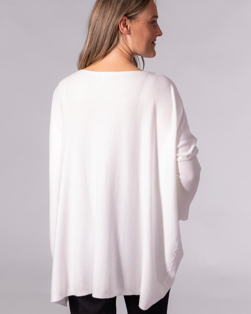 Back view of a cream cotton knit jumper showcasing an oversized draped silhouette with drop shoulders and fitted sleeves.