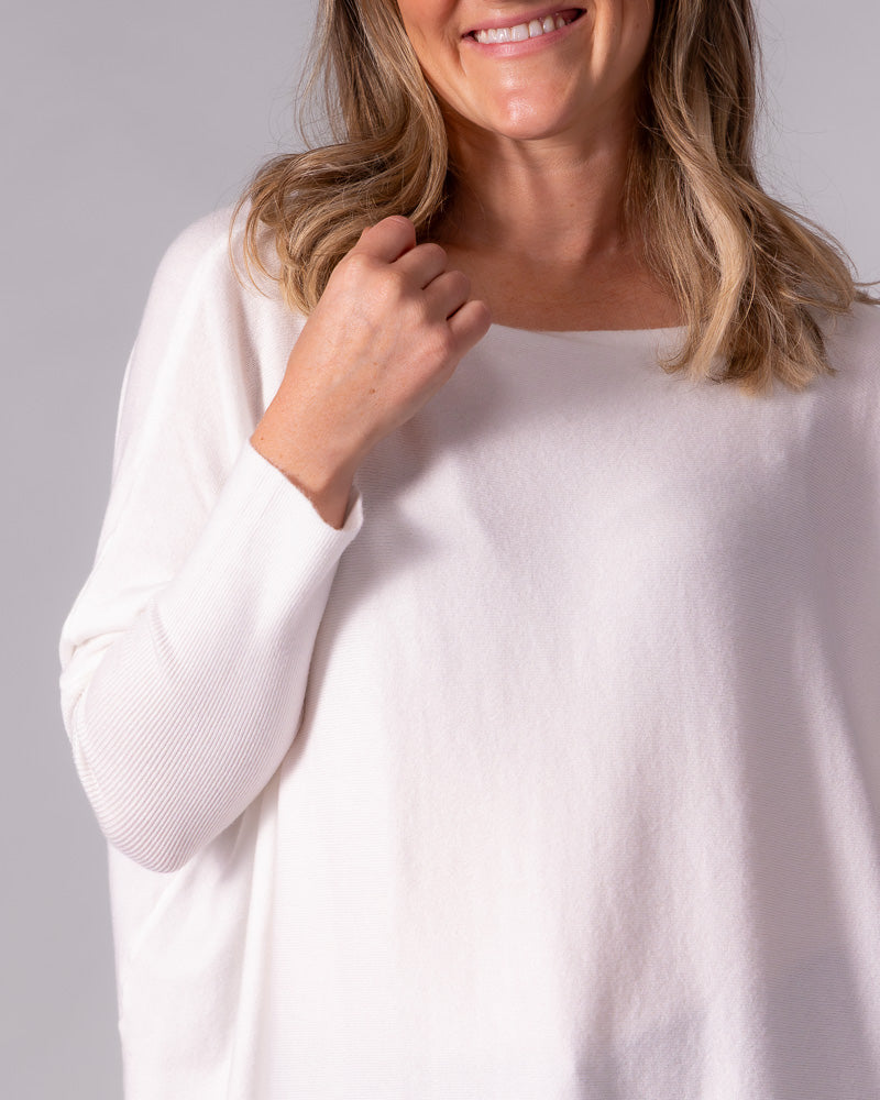 Cream cotton knit jumper featuring a wide boat neckline, drop shoulder design, and fine ribbed texture on the sleeve.