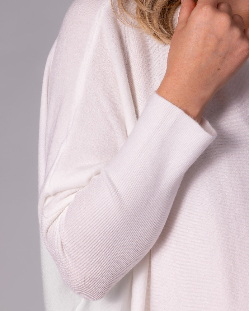 Cream cotton jumper featuring a fine knit body, relaxed drop shoulder, and a fitted ribbed lower sleeve.