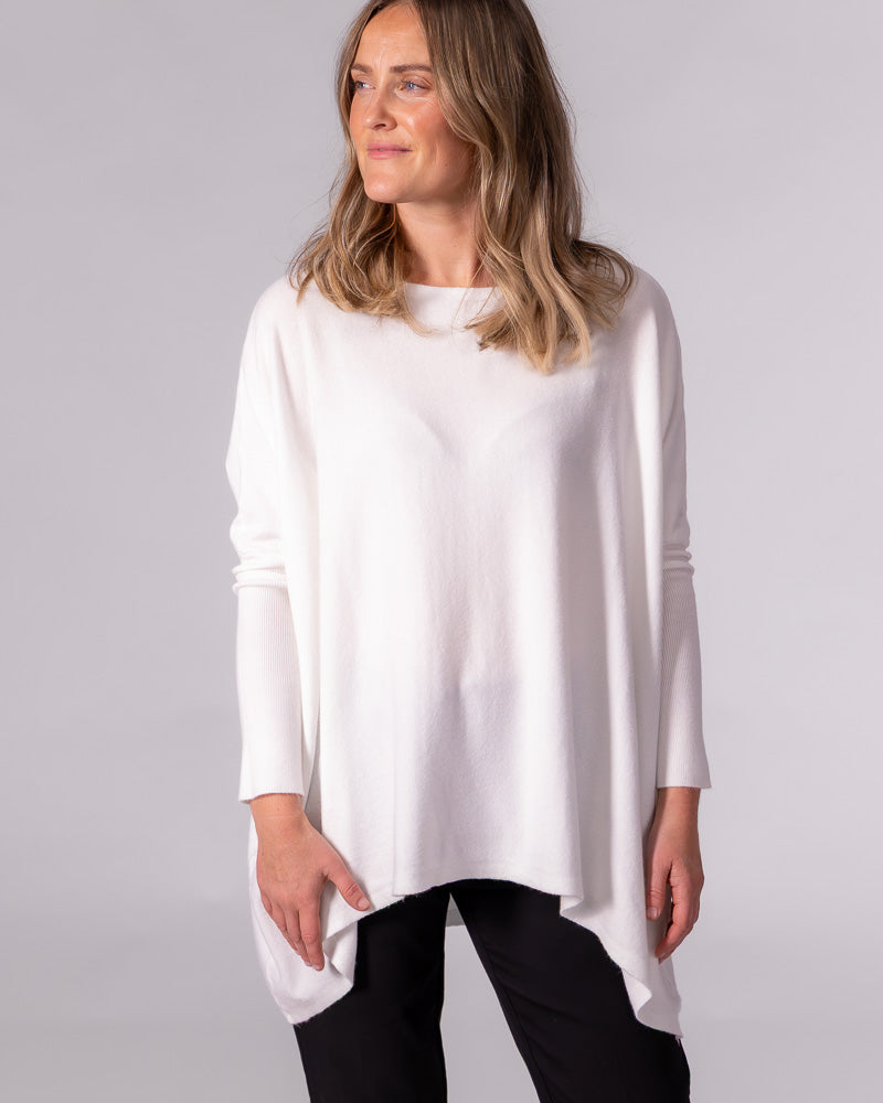 Oversized cream cotton knit jumper featuring a wide boat neckline, fitted sleeves, and a draped hi-low hem.