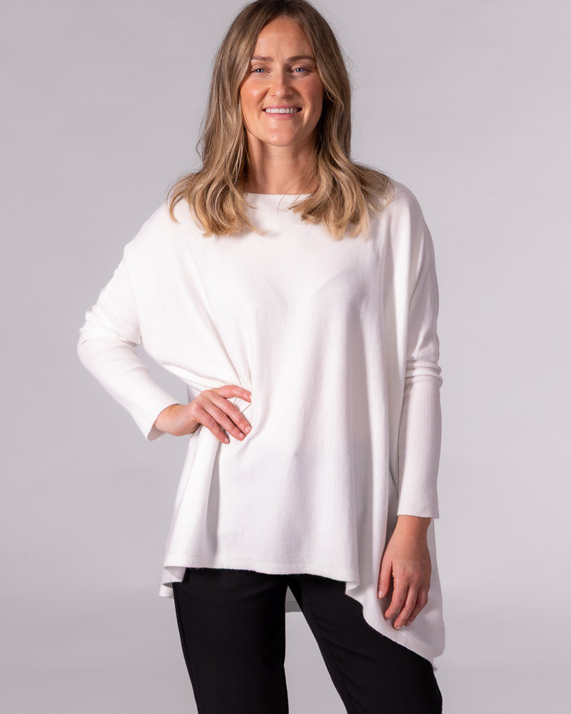 Oversized cream cotton knit jumper featuring a wide boat neckline, fitted ribbed sleeves, and a draped hi-low hem.