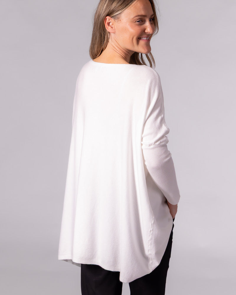 Back view of a cream oversized cotton jumper featuring a wide neckline, draped back hem, and long fitted sleeves.