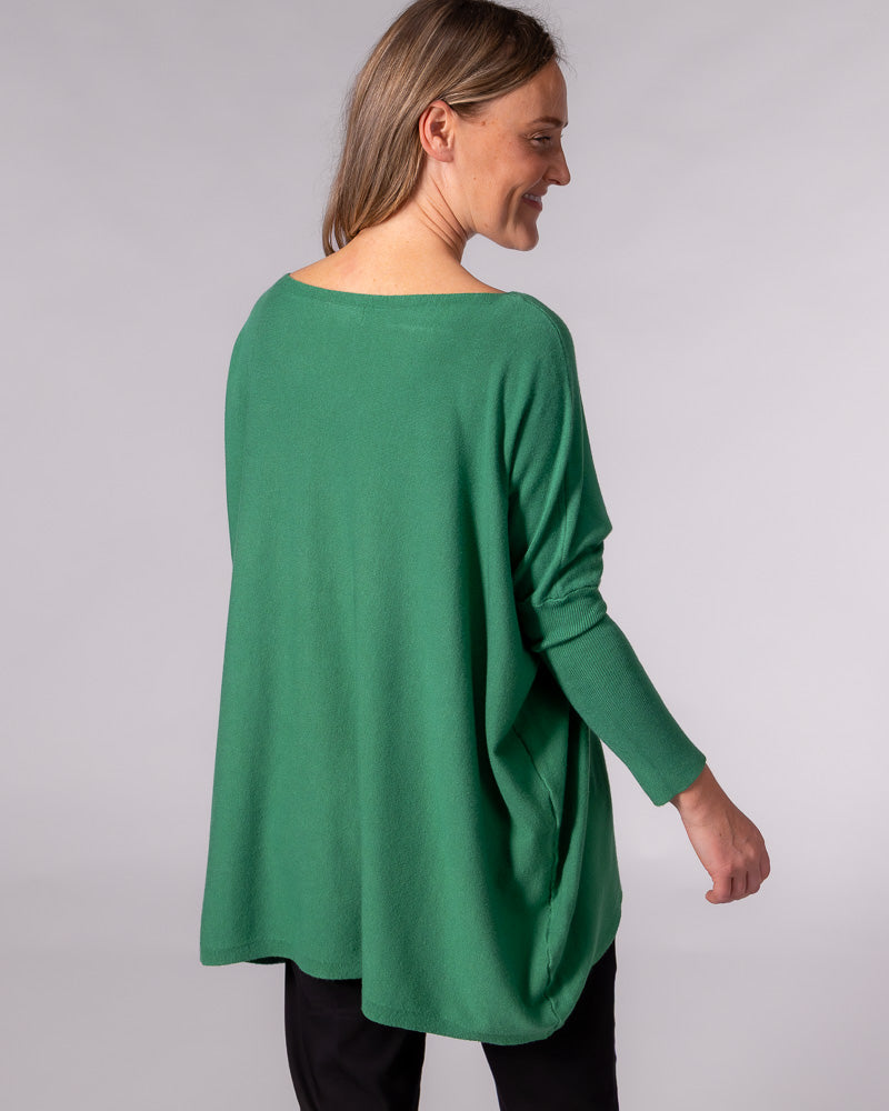 Back view of an oversized green cotton jumper featuring a wide neckline, draped silhouette, and fitted sleeves.