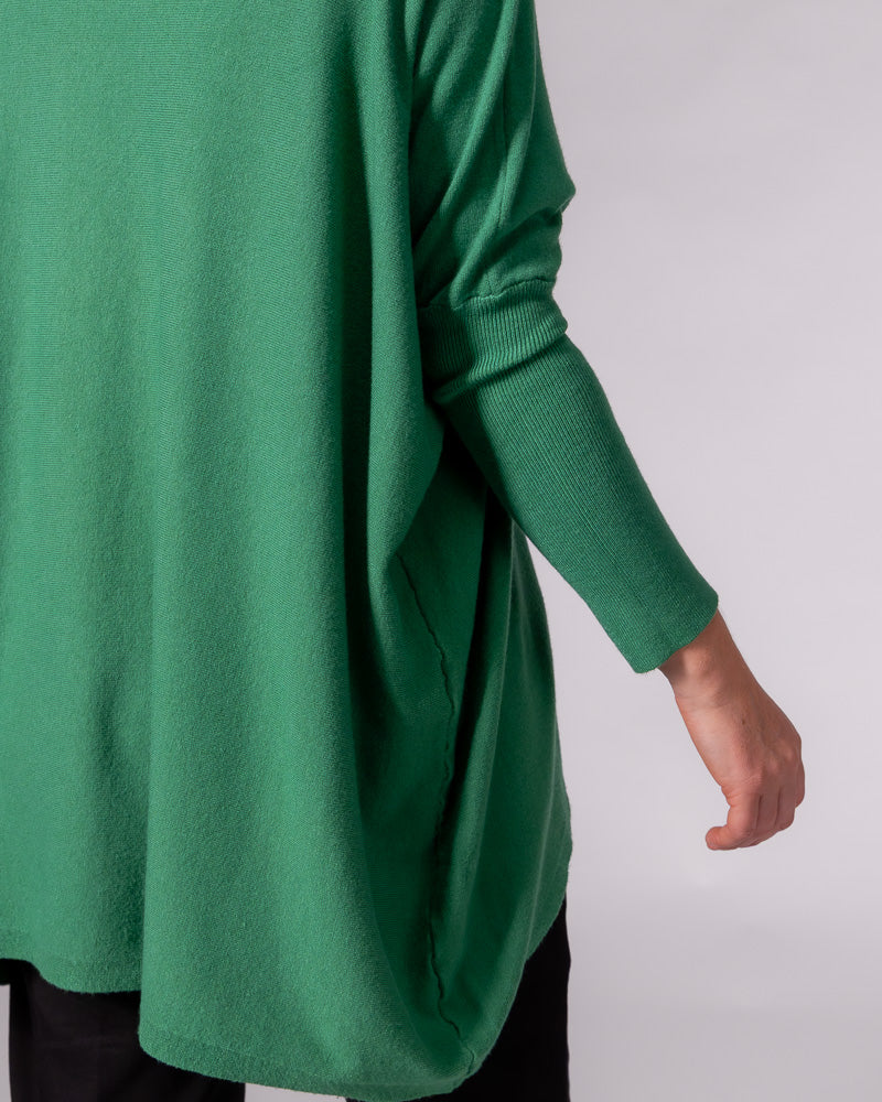 Green cotton knit jumper displaying an oversized draped body, dropped shoulder seam, and fitted ribbed lower sleeve.