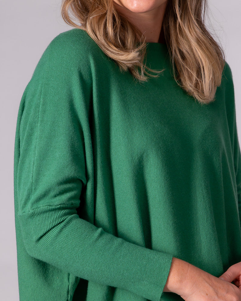 Green oversized cotton knit jumper featuring a wide neckline, draped body, drop shoulder, and fitted ribbed sleeve.
