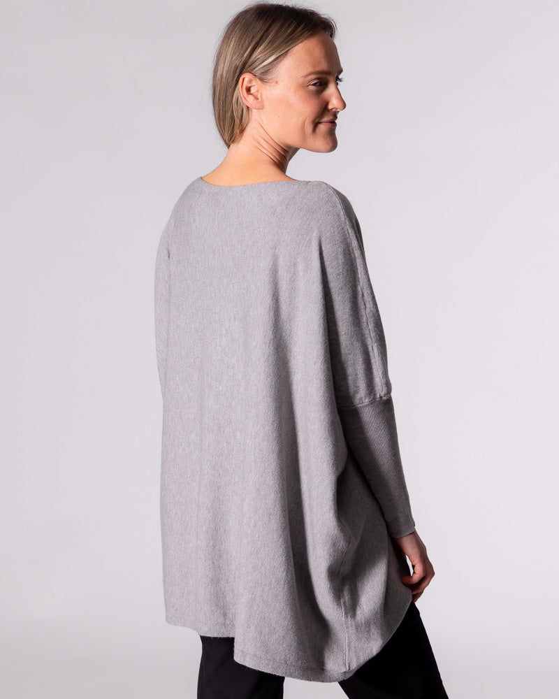 Rear angle of the Karma Kameleon grey jumper, highlighting the extended drape back hemline and relaxed fit.