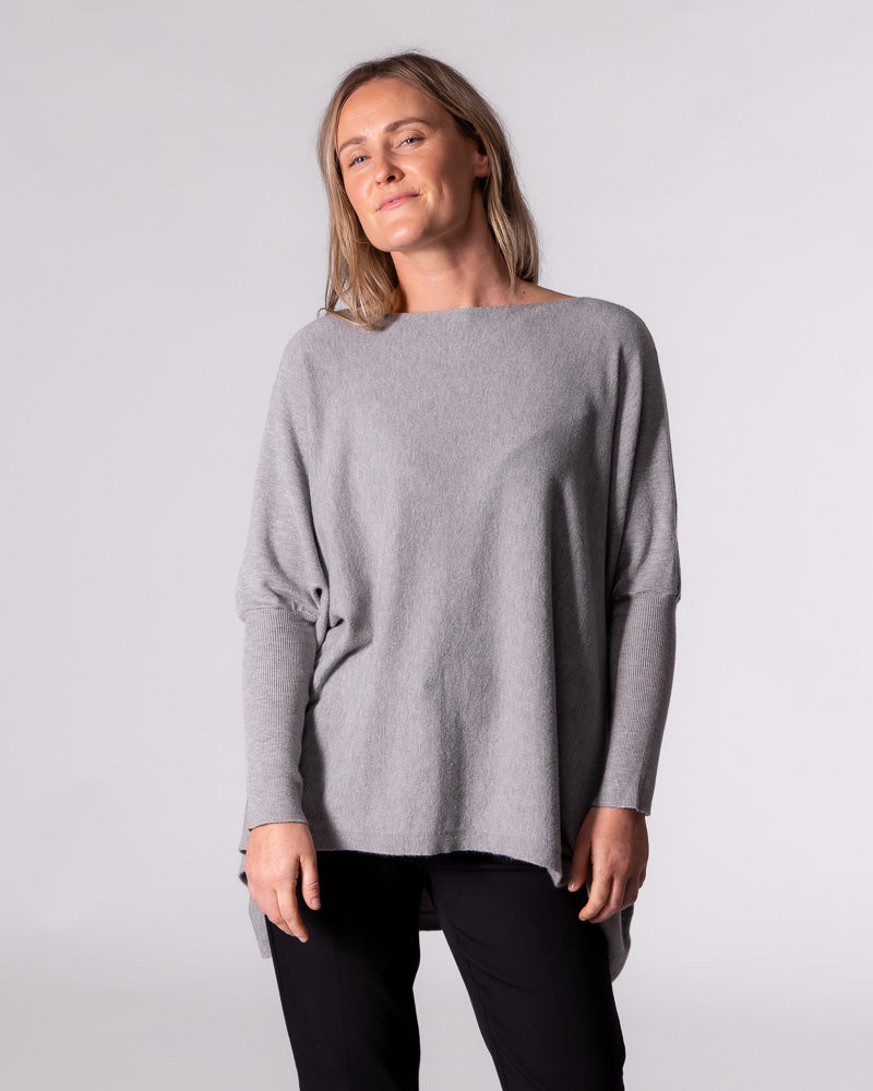 Front facing view of the relaxed grey jumper showcasing the hi-low hemline sitting noticeably higher at the front.