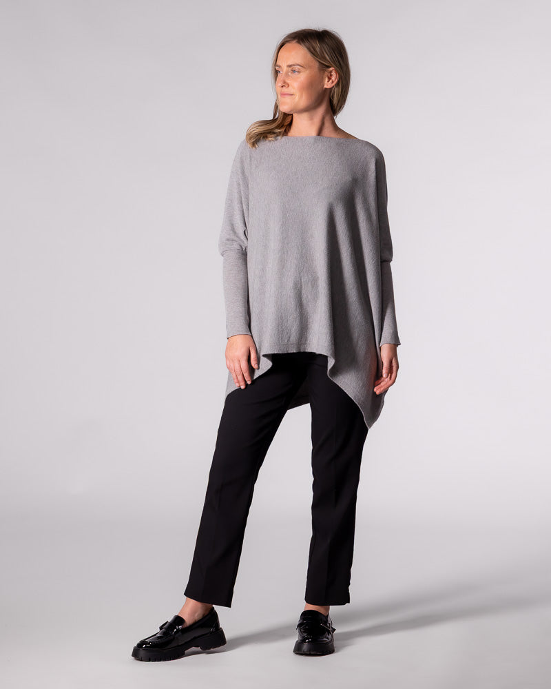 Full-length styling of the oversized grey knit top paired with tailored black pants and chunky black loafers.