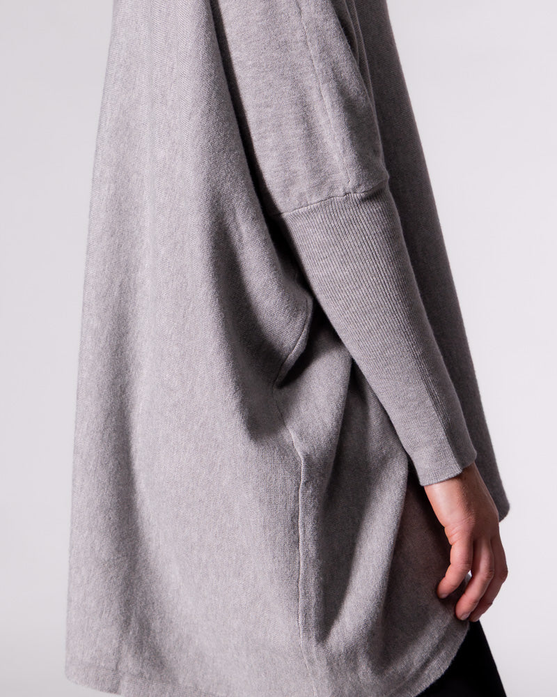 Side profile of the grey Karma Kameleon knitwear demonstrating the ribbed sleeve and relaxed drape of the body.