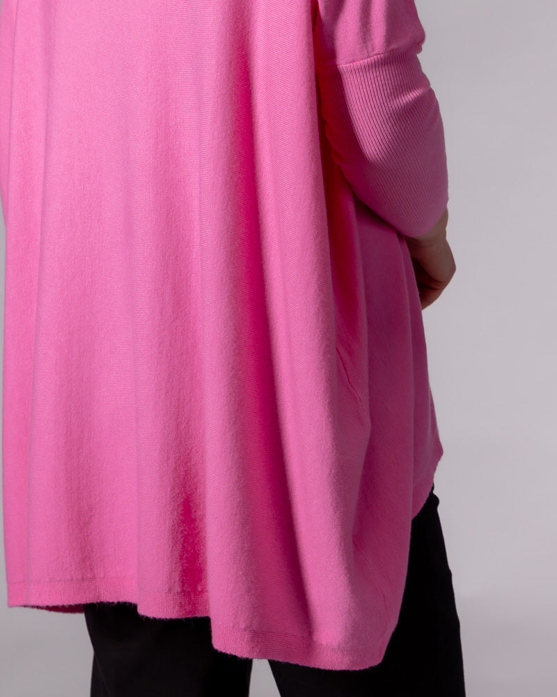 Hot pink oversized cotton knit jumper featuring a draped back silhouette and ribbed fitted sleeve.
