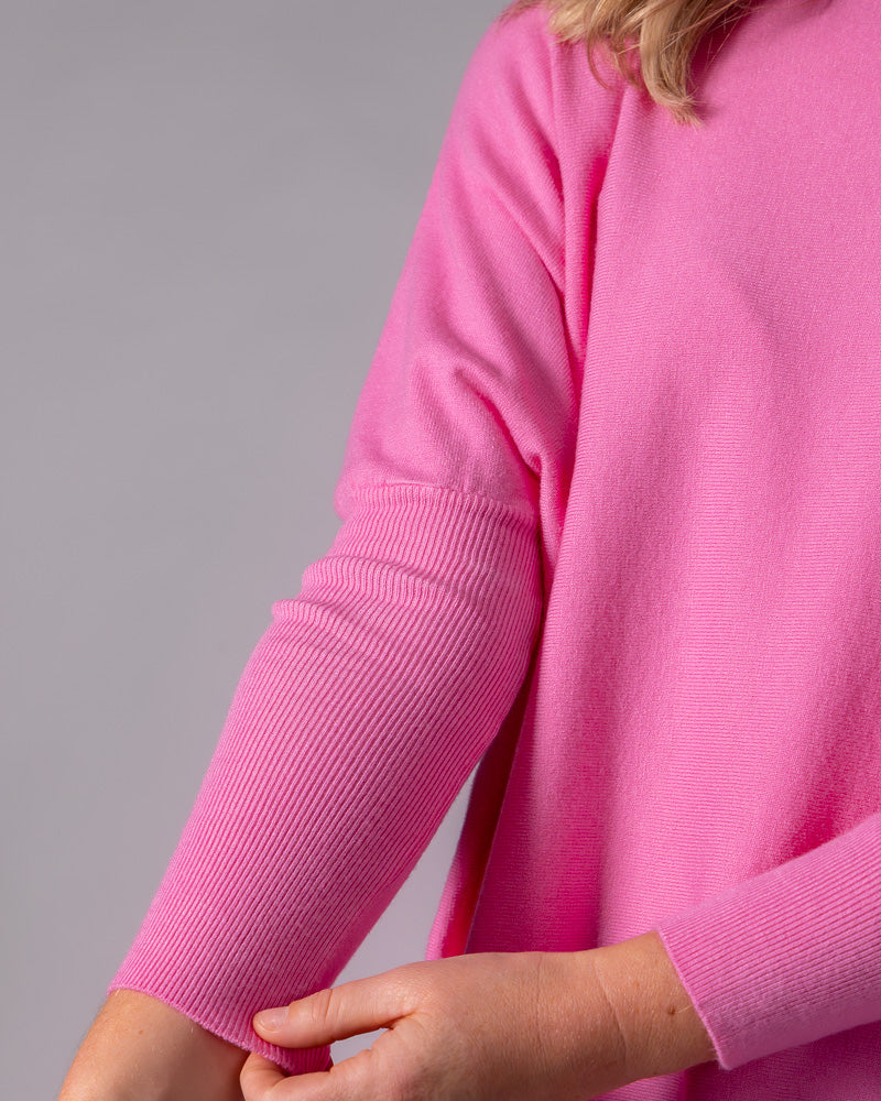 Hot pink cotton jumper highlighting the contrasting ribbed texture of the fitted lower sleeve against the relaxed body.