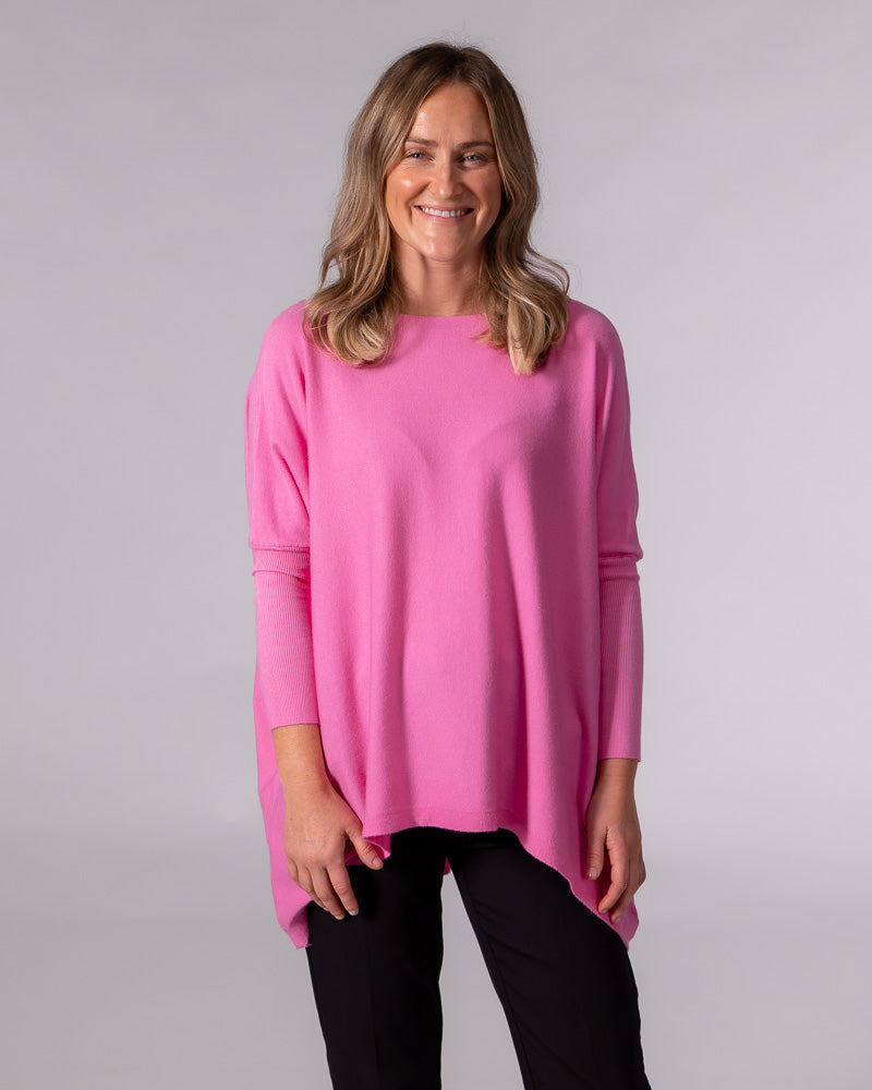 Oversized hot pink cotton jumper with a wide boat neckline, drop shoulders, ribbed fitted sleeves, and a hi-low hem.