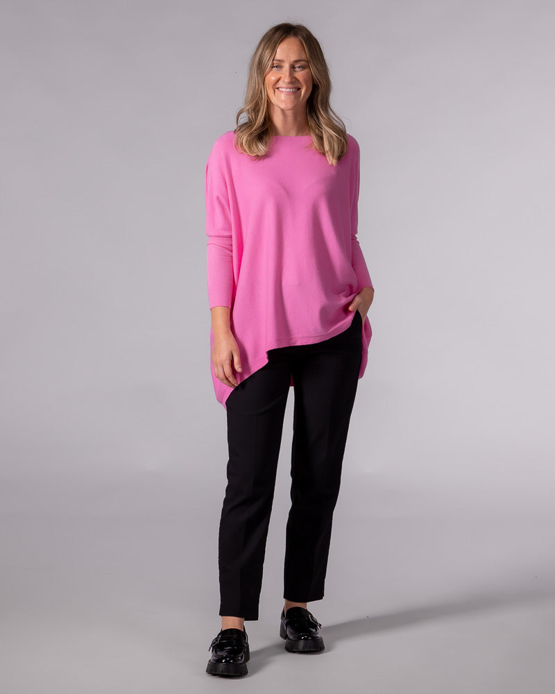 Oversized hot pink cotton knit jumper featuring a wide boat neckline, dropped shoulders, and a draped hi-low hem.