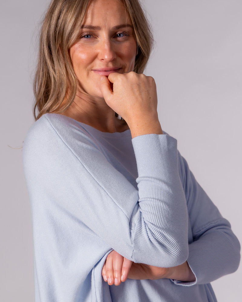 Light blue oversized cotton jumper featuring a wide boat neckline, drop shoulders, and fitted ribbed sleeves.