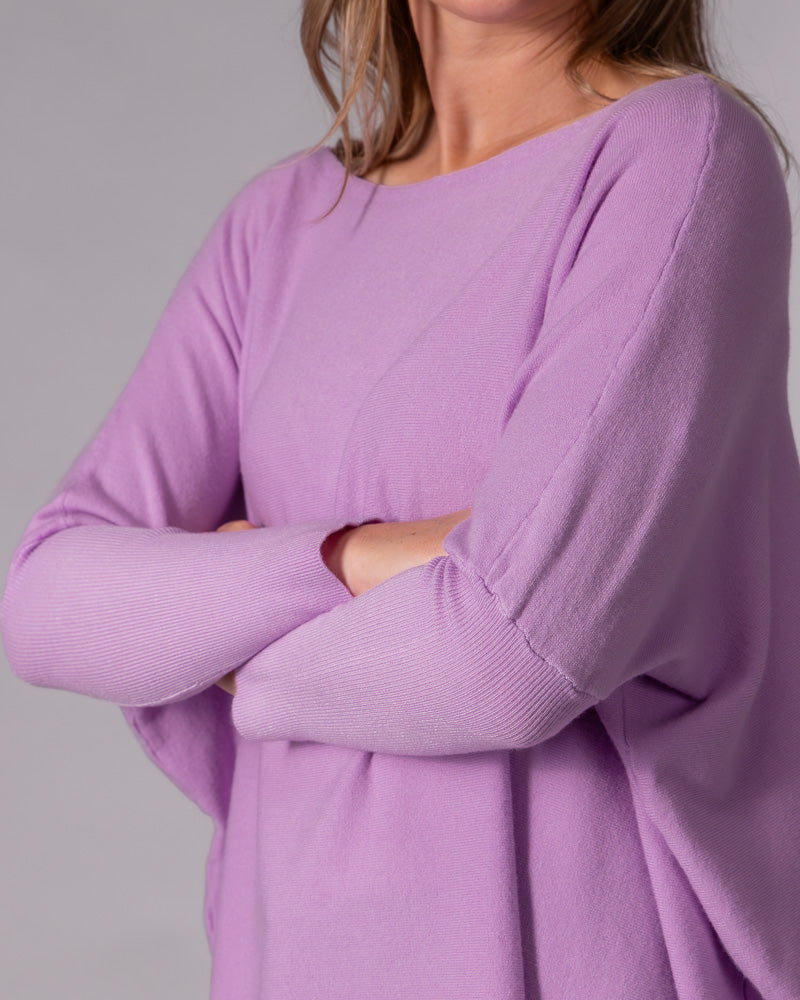Oversized lilac cotton knit jumper featuring a wide boat neckline, draped body, and ribbed fitted lower sleeves.